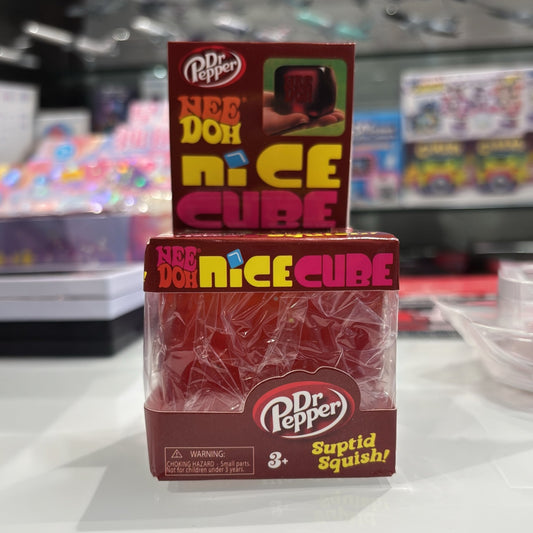A Dr. Pepper Nee Doh Nice Cube toy product in its retail packaging, sitting on a white counter with a blurred store background.