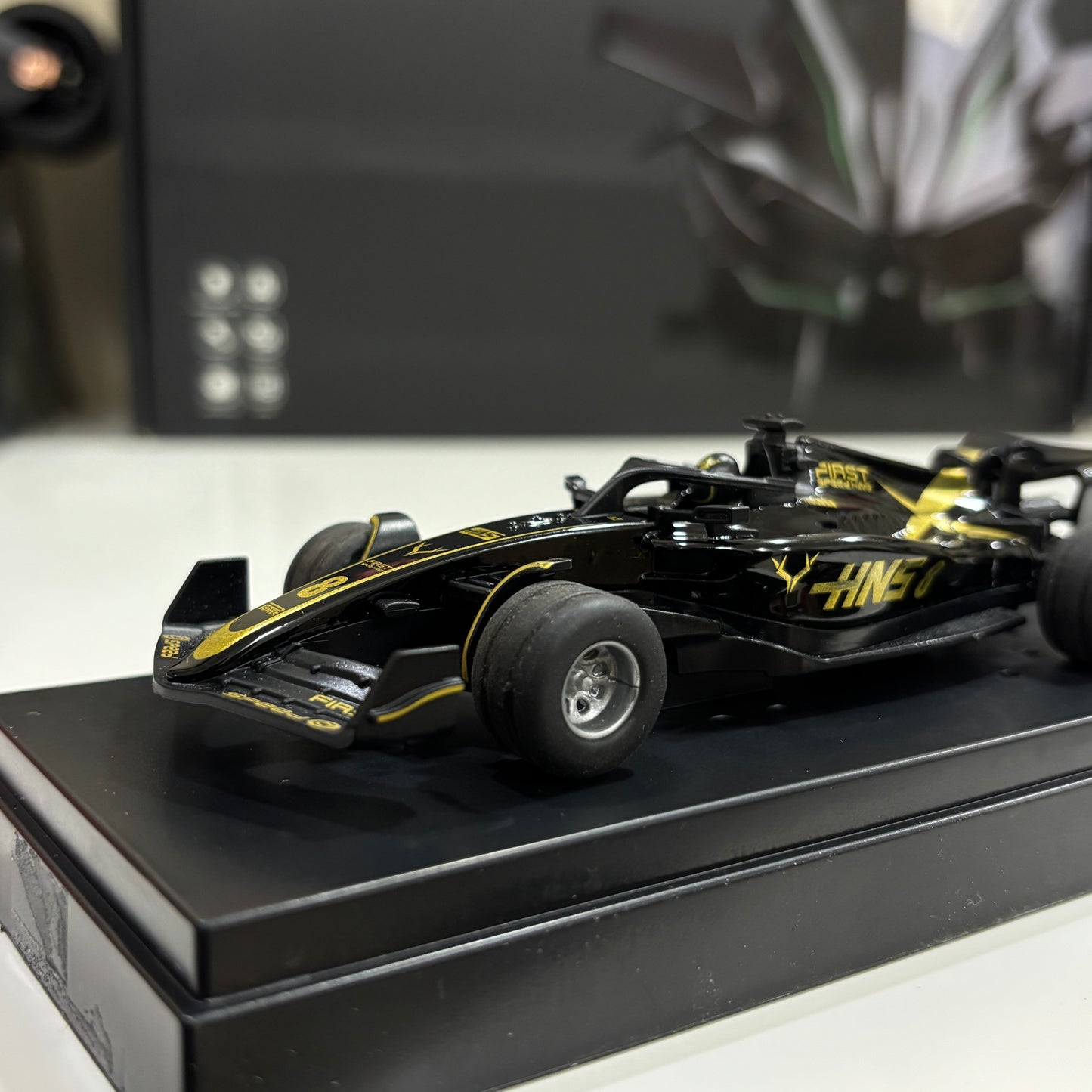 Black and yellow model racing car on a black platform with a blurred background