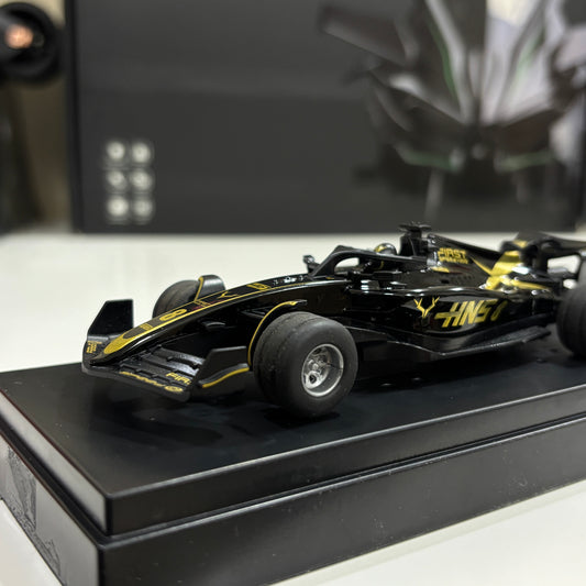 Black and yellow model racing car on a black platform with a blurred background